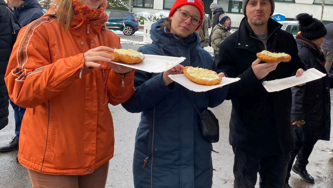 Három ember jóízűen eszi a sajtos-tejfölös lángost