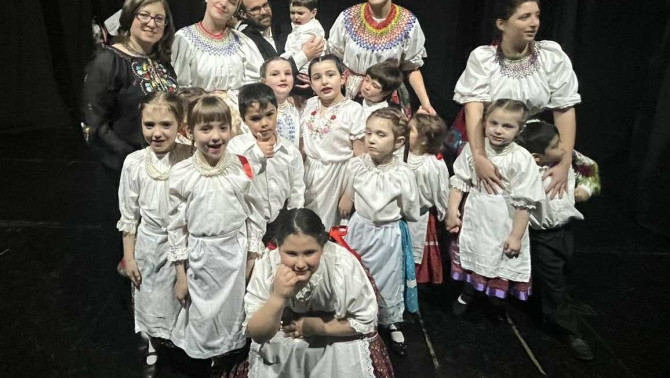 A gyermektáncegyüttes tagjai izgatottan várják a műsort a színpadon.